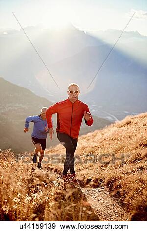 Stock Photo - "Trail runners on dirt track, Valais, Switzerland". Fotosearch
