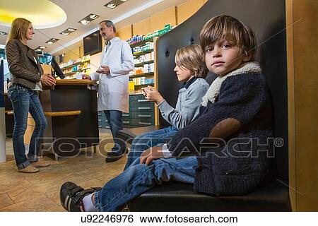 Two brothers waiting whilst mother is talking to pharmacist in a drugstore View Large Photo Image Stock Photograph - Two brothers waiting whilst mother is talking to pharmacist in a drugstore. Fotosearch