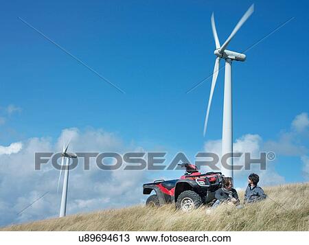 Stock Image - Two brothers with quadbike at windfarm. Fotosearch