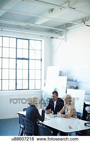 Stock Photo - Two businesswomen and man talking at office meeting. Fotosearch
