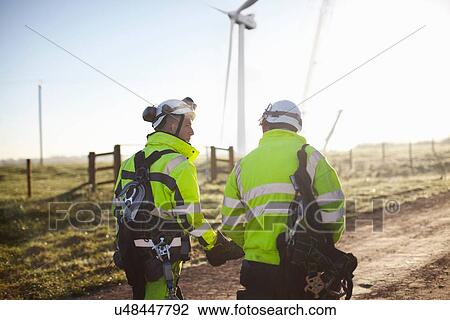"Two engineers at wind farm, walking together, rear view" View Large Photo Image Stock Image - "Two engineers at wind farm, walking together, rear view". Fotosearch