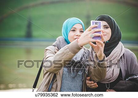 Two female friends at lakeside taking smartphone selfie View Large Photo Image Stock Image - Two female friends at lakeside taking smartphone selfie. Fotosearch
