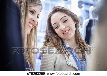 Two female friends browsing at dresses in boutique View Large Photo Image Stock Photo - Two female friends browsing at dresses in boutique. Fotosearch