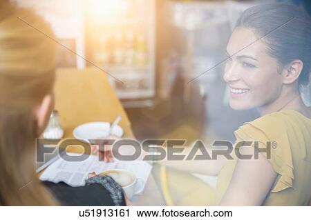 Two female friends having coffee together in cafe View Large Photo Image Stock Image - Two female friends having coffee together in cafe. Fotosearch