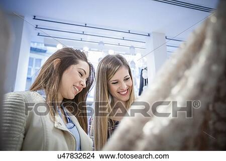 Two female friends shopping for dresses in boutique View Large Photo Image Picture - Two female friends shopping for dresses in boutique. Fotosearch