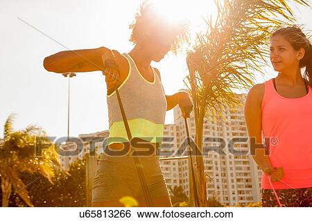 Two female friends training with exercise bands in park View Large Photo Image Stock Photograph - Two female friends training with exercise bands in park. Fotosearch
