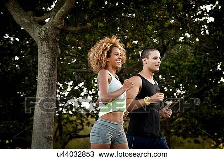 Stock Image - Two friends doing training run in park. Fotosearch