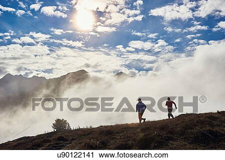 Stock Image - "Two men trail running, Valais, Switzerland". Fotosearch