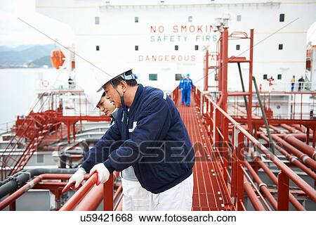 Stock Photo - "Two workers having discussion at shipping port, GoSeong-gun, South Korea". Fotosearch