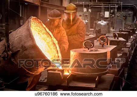 Two workers pouring molten metal from flask in foundry View Large Photo Image Stock Photograph - Two workers pouring molten metal from flask in foundry. Fotosearch