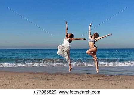 Two young female dancers leaping mid air on beach View Large Photo Image Stock Photo - Two young female dancers leaping mid air on beach. Fotosearch
