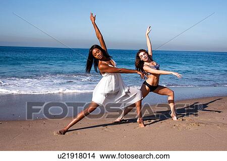 Two young female dancers poised with arms raised on beach View Large Photo Image Picture - Two young female dancers poised with arms raised on beach. Fotosearch