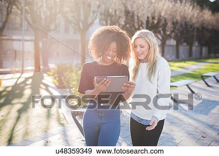 "Two young female friends in park looking at digital tablet, Como, Italy" View Large Photo Image Stock Photo - "Two young female friends in park looking at digital tablet, Como, Italy". Fotosearch