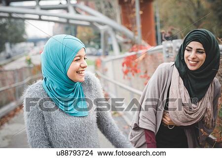 Two young female friends laughing on park path View Large Photo Image Picture - Two young female friends laughing on park path. Fotosearch