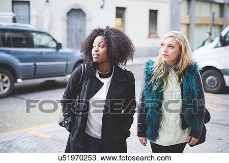 Stock Image - "Two young female friends on street, Como, Italy". Fotosearch