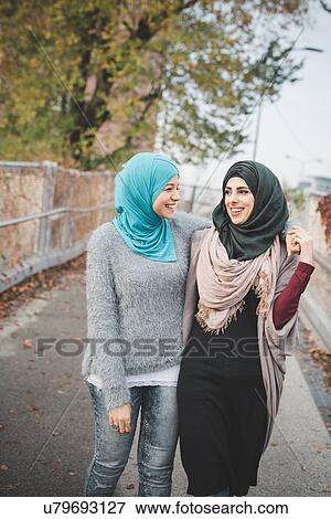Two young female friends walking and chatting on park path View Large Photo Image Stock Photo - Two young female friends walking and chatting on park path. Fotosearch