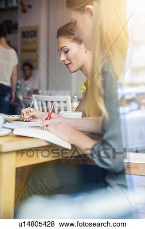 Stock Photo - "Two young women having meeting in cafe, view through window". Fotosearch