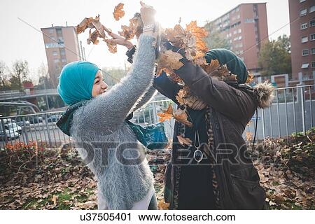Two young women in park play fighting with autumn leaves View Large Photo Image Stock Image - Two young women in park play fighting with autumn leaves. Fotosearch