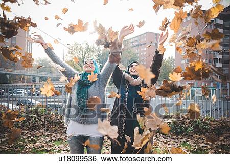 Two young women in park throwing autumn leaves View Large Photo Image Stock Photograph - Two young women in park throwing autumn leaves. Fotosearch