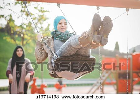 Two young women playing on playground swings View Large Photo Image Stock Photo - Two young women playing on playground swings. Fotosearch