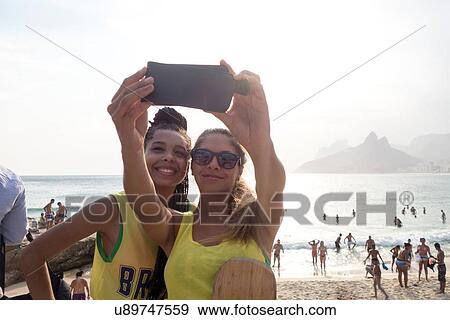 "Two young women posing for smartphone selfie on Ipanema beach, Rio De Janeiro, Brazil" View Large Photo Image Stock Photo - "Two young women posing for smartphone selfie on Ipanema beach, Rio De Janeiro, Brazil". Fotosearch