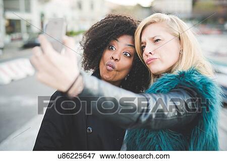 "Two young women pulling faces for smartphone selfie, Lake Como, Como, Italy" View Large Photo Image Stock Photo - "Two young women pulling faces for smartphone selfie, Lake Como, Como, Italy". Fotosearch