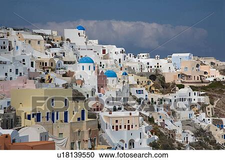 Stock Image - "View of painted and white washed hillside town, Oia, Santorini, Cyclades, Greece". Fotosearch