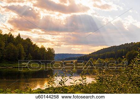 Stock Photo - "View of sunbeams over river landscape, Sarsy village, Sverdlovsk Region, Russia". Fotosearch