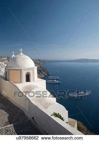 Stock Image - "View of white washed church and sea ferries, Oia, Santorini, Cyclades, Greece". Fotosearch