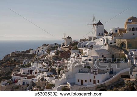 Stock Image - "View of white washed hillside town and windmills, Oia, Santorini, Cyclades, Greece". Fotosearch