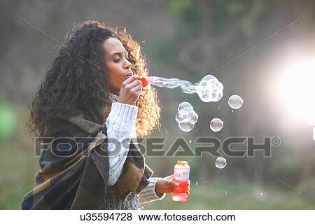 Woman blowing soap bubbles in countryside View Large Photo Image Stock Photo - Woman blowing soap bubbles in countryside. Fotosearch