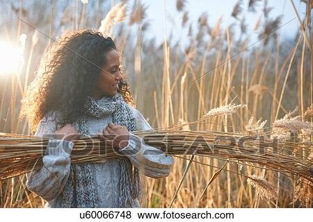 Stock Photo - Woman carrying bundle of wheat. Fotosearch