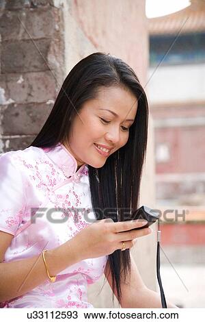 "Woman in chinese dress texting on cell phone, Beijing, China" View Large Photo Image Stock Image - "Woman in chinese dress texting on cell phone, Beijing, China". Fotosearch