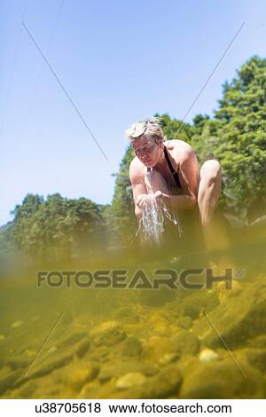 Stock Photo - "Woman splashing face with water in river, Coromandel Peninsula, North Island, New Zealand". Fotosearch