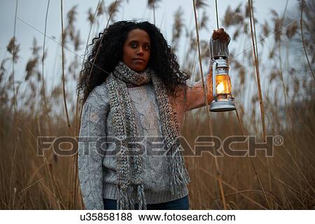 Stock Photo - Woman using paraffin lamp in countryside. Fotosearch
