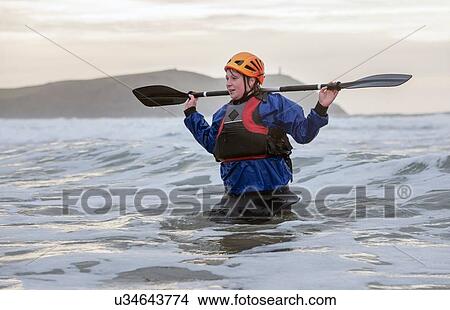 Woman wearing helmet holding oar in sea View Large Photo Image Picture - Woman wearing helmet holding oar in sea. Fotosearch