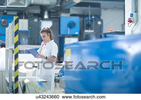 Stock Image - Woman working at machinery in laundry. Fotosearch