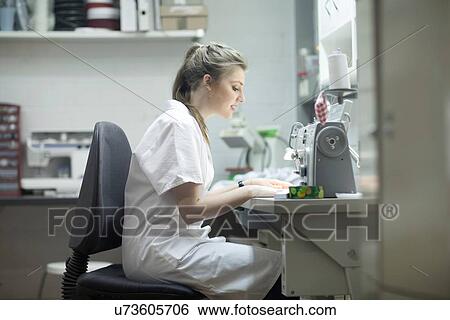 Stock Photograph - Woman working at sewing machine at laundry. Fotosearch
