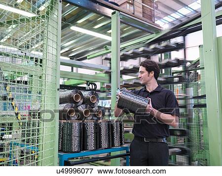 Stock Photo - Worker carrying carbon fibre thread in carbon fibre factory. Fotosearch