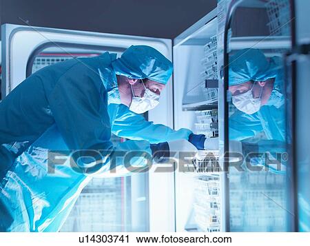 Stock Image - Worker checking archived electronic components in nitrogen atmosphere in clean room laboratory. Fotosearch