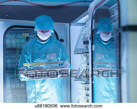 Stock Photograph - Worker checking archived electronic components in nitrogen atmosphere in clean room laboratory. Fotosearch