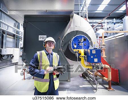 Stock Photograph - Worker checking readings on digital tablet in gas fired power station. Fotosearch