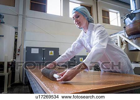 Picture - Worker cutting confectionery fudge in chocolate factory. Fotosearch