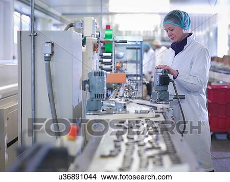 Picture - Worker inspecting chocolate on production line in chocolate factory. Fotosearch
