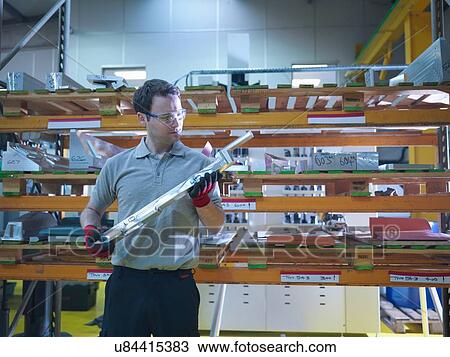 Stock Image - Worker inspecting part of mould in plastics factory. Fotosearch