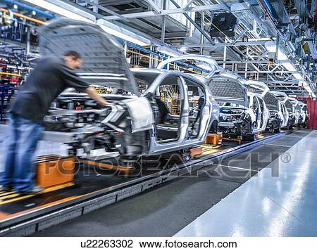 Stock Image - Worker on car production line in car factory. Fotosearch