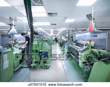 Stock Image - Worker operating carbon fibre loom in carbon fibre factory. Fotosearch