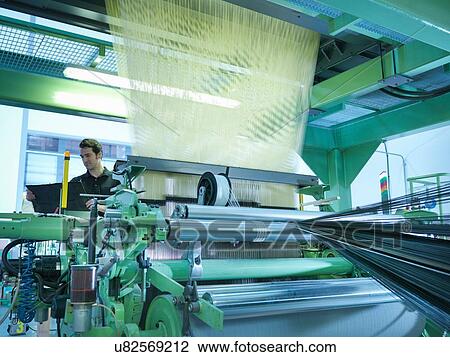 Stock Image - Worker operating carbon fibre loom in carbon fibre factory. Fotosearch