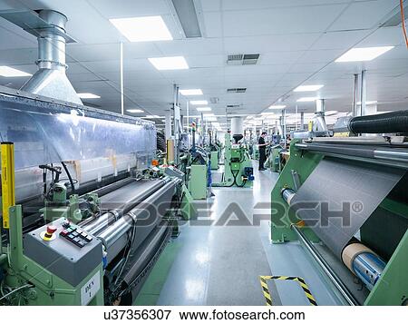 Stock Photo - Worker operating carbon fibre loom in carbon fibre factory. Fotosearch