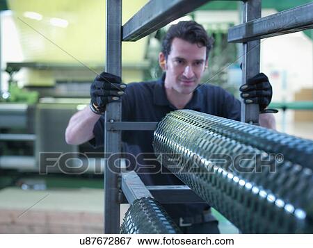 Stock Photo - Worker operating carbon fibre loom in carbon fibre factory. Fotosearch